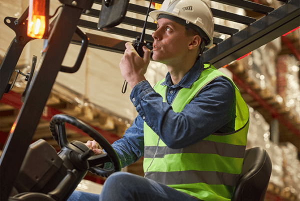 How to drive a forklift safely: essential safety tips Warehouse operator demonstrating how to drive a forklift safely while using a two-way radio