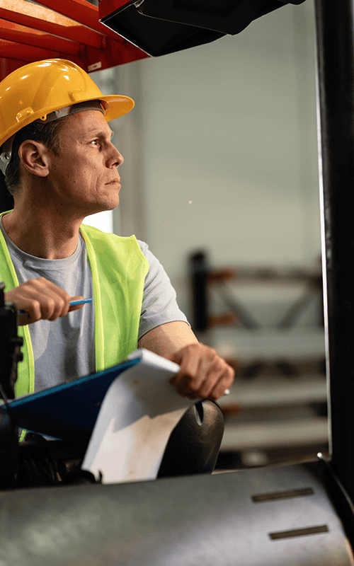 Forklift operator following the 5 safety rules for forklifts in a busy warehouse