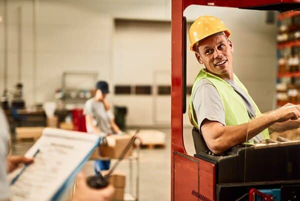 Instructor guiding a seated operator during forklift refresher training